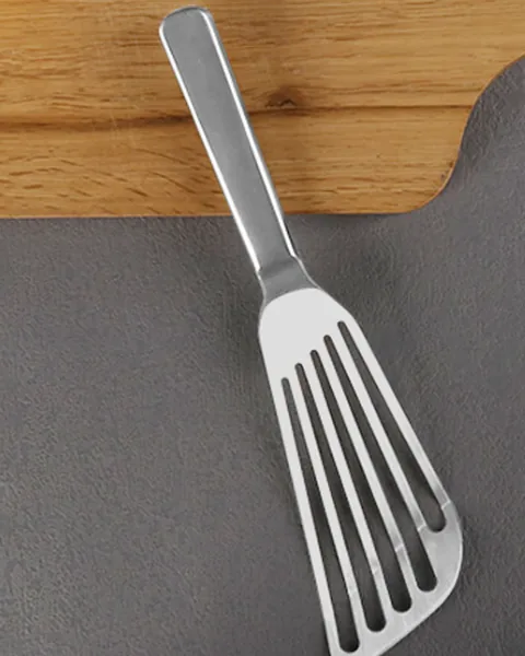 Slotted stainless steel fish spatula resting on a cutting board